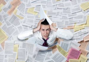 Homme noyé par les papiers souhaitant utiliser la dématérialisation dans une démarche de développement durable 