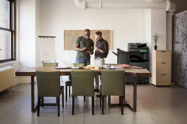 Deux hommes qui regardent un smartphone à côté d'une imprimante à encre effaçable